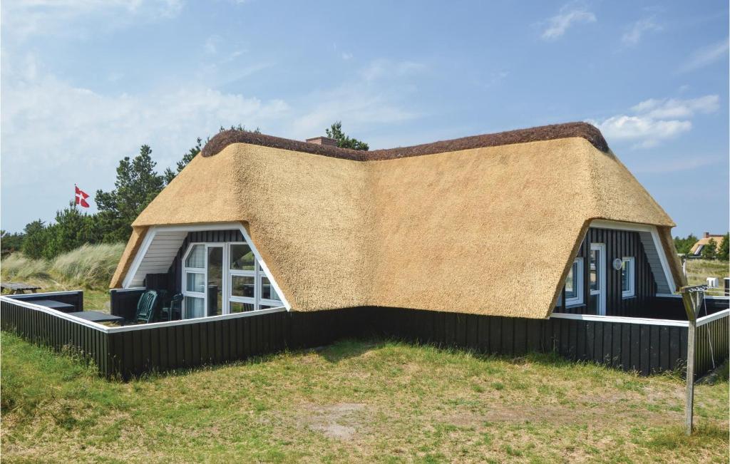 a house with a thatched roof on a field at Stunning Home In Blvand With Sauna in Blåvand