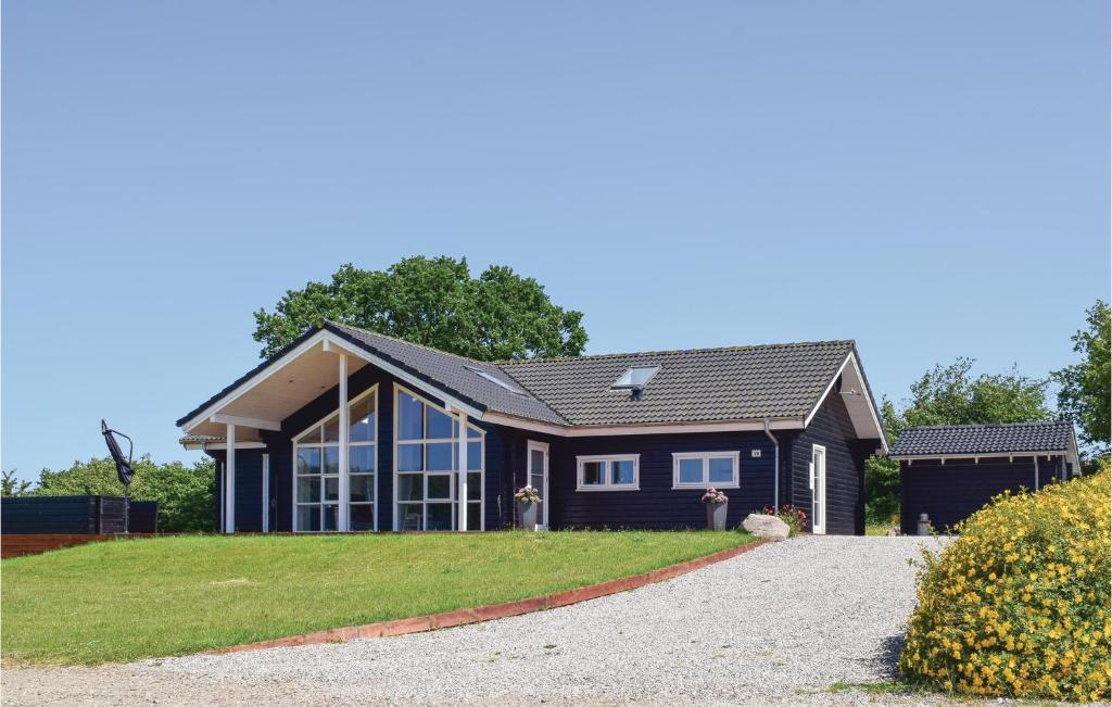 una casa con una casa negra con una entrada de grava en Awesome Home In Rudkbing With Sauna, en Spodsbjerg