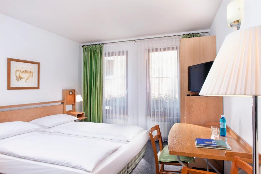 a hotel room with a bed and a desk with a computer at Hotel Agneshof Nürnberg in Nuremberg