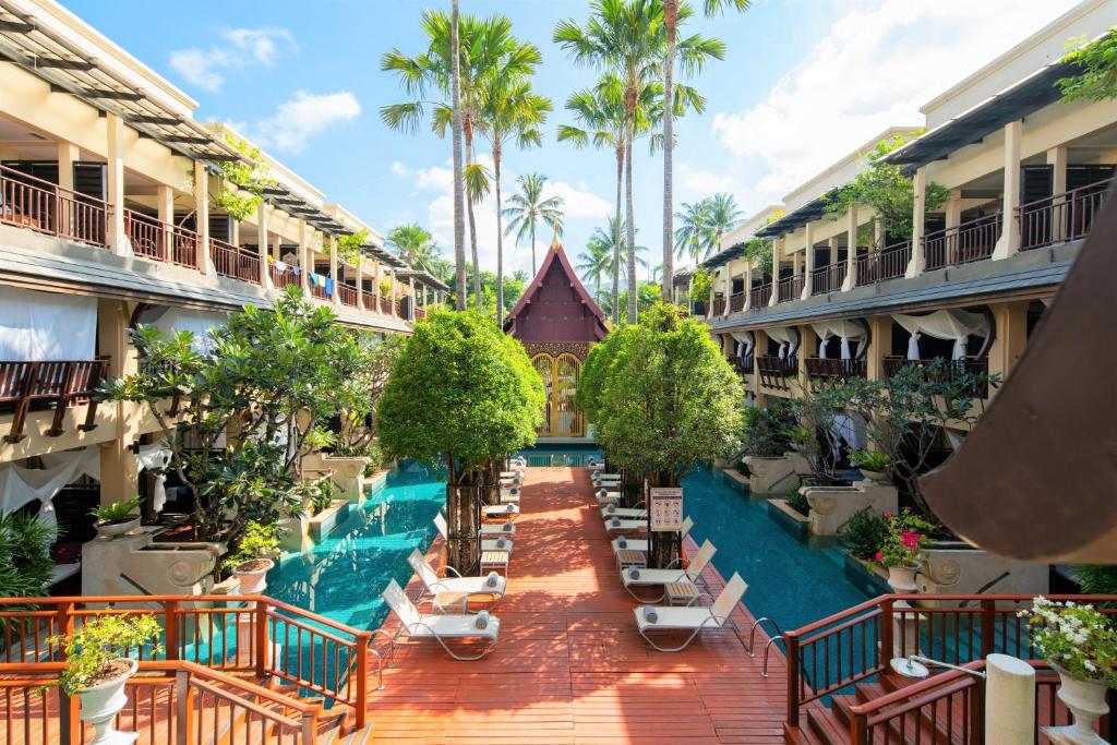 um pátio de hotel vazio com uma piscina e palmeiras em Burasari Phuket Resort & Spa em Praia de Patong