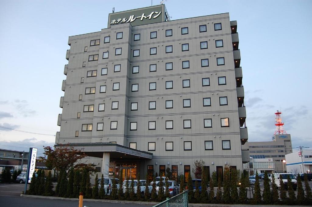 Um edifício alto e cinzento com um sinal. em Hotel Route-Inn Fukui Owada em Fukui