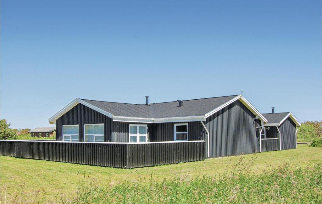 Ein schwarzes Haus mit einem Zaun auf einem Feld in der Unterkunft Gorgeous Home In Lkken With Wifi in Løkken