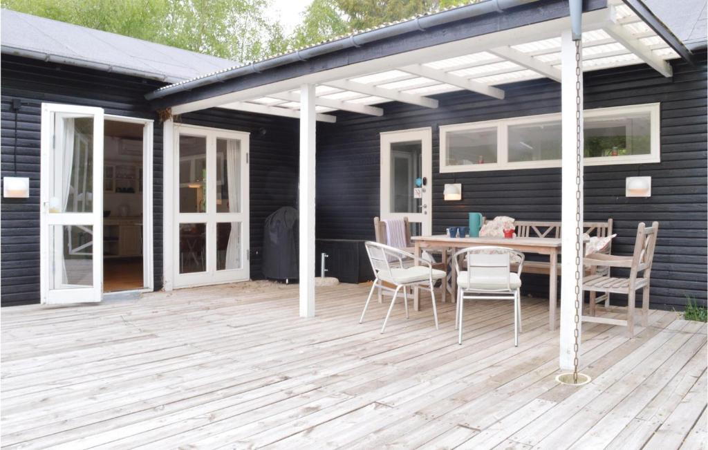 GræstedにあるThree-Bedroom Holiday Home In Grastedのデッキにテーブルと椅子が置かれたパティオ