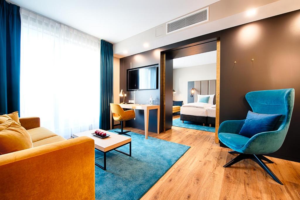 ネッカーズルムにあるWelcome Hotel Neckarsulmのリビングルーム(ソファ付)、ベッドルーム1室が備わります。