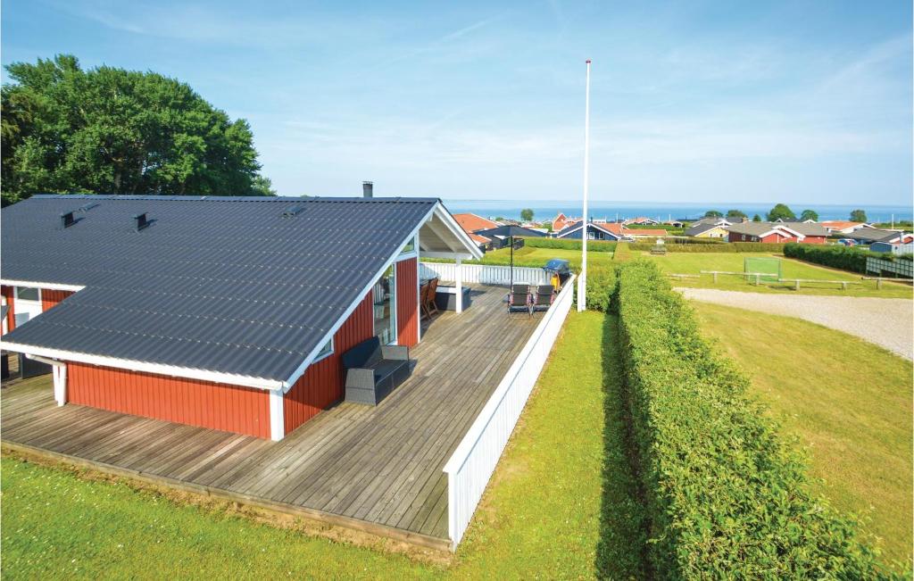 un pequeño edificio rojo con terraza de madera en Amazing Home In Sjlund With Wifi en Sønder Bjert