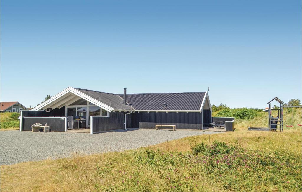 a black building with benches in front of a playground at Three-Bedroom Holiday Home In Hvide Sande in Bjerregård
