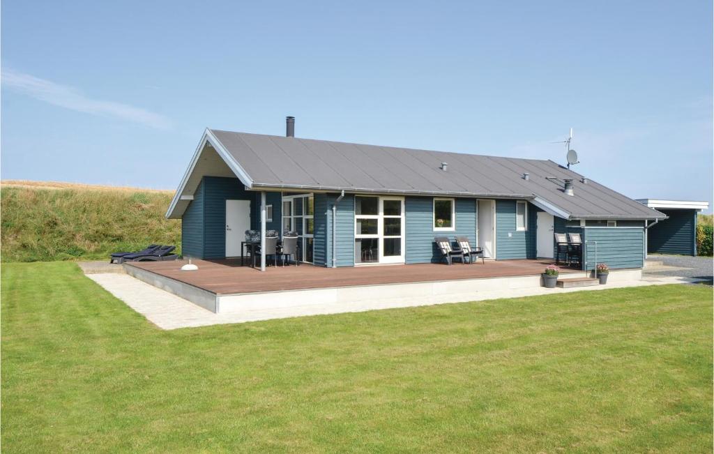 a blue house with a deck in a field at Awesome Home In Knebel With 3 Bedrooms, Sauna And Wifi in Knebel