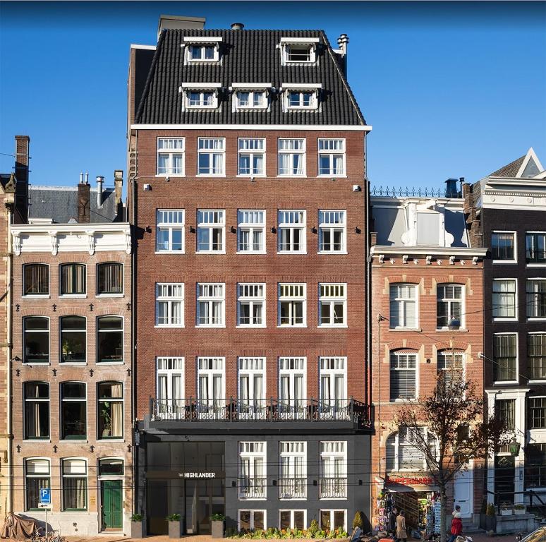 a tall red brick building with a black roof at The Highlander in Amsterdam