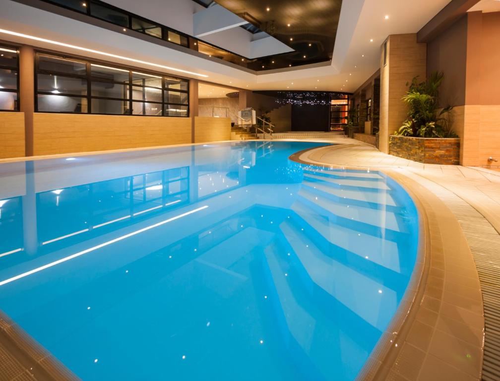 - une grande piscine d'eau bleue dans un bâtiment dans l'établissement Hôtel Restaurant Les Alizés, à Lipsheim