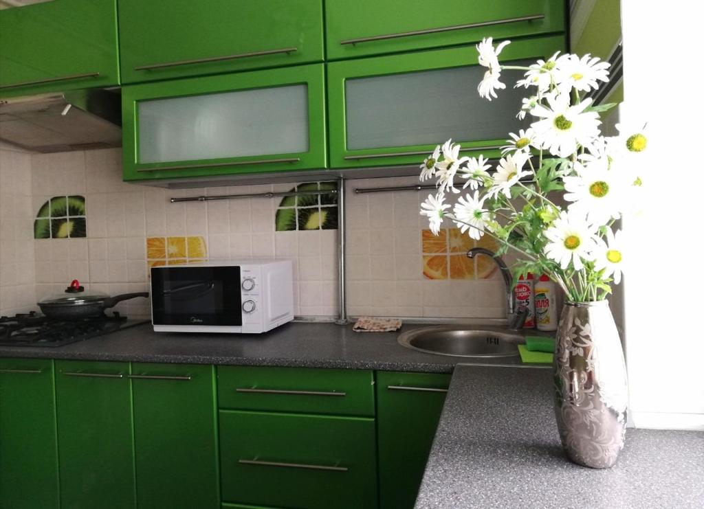 a kitchen with green cabinets and a vase of flowers at Апартаменты MANGO в парке имени Суворова in Kobryn