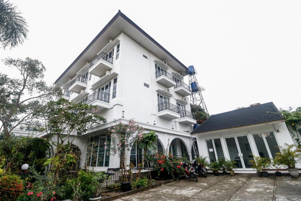 Un bâtiment blanc avec des fleurs devant lui dans l'établissement RedDoorz Syariah At Lampung Walk, à Bandar Lampung