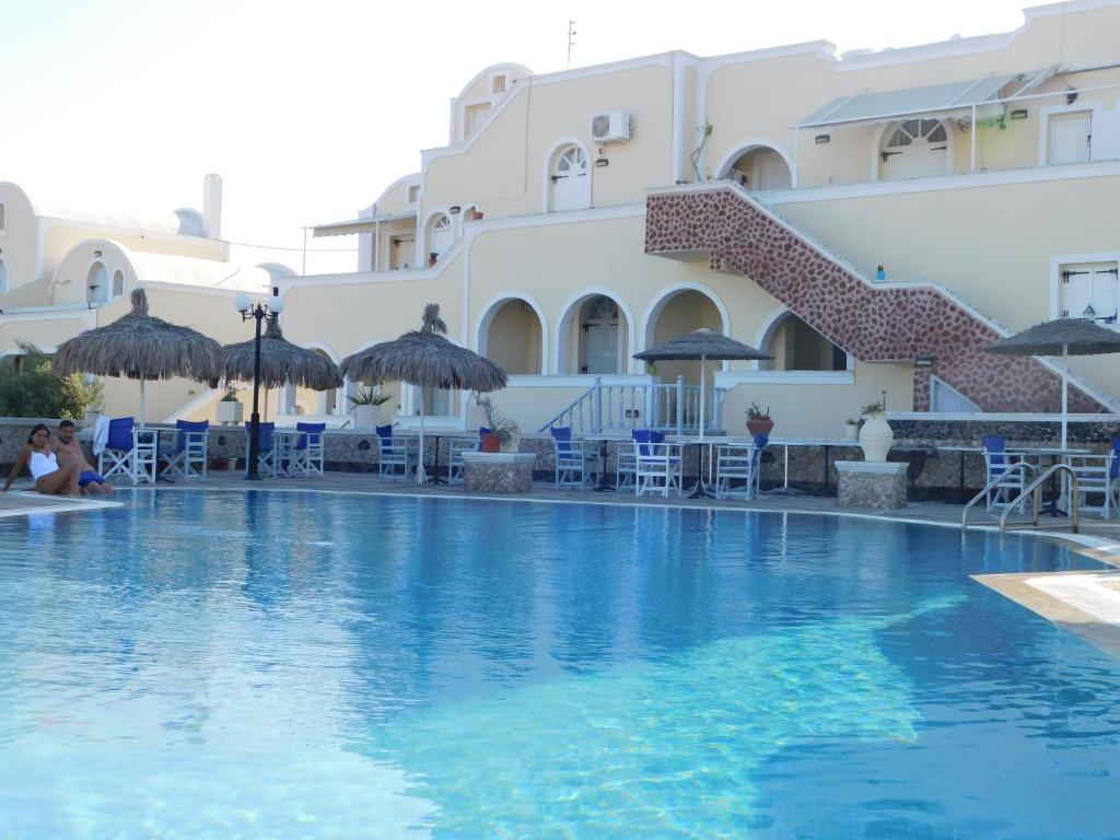 una piscina en un hotel con sillas y sombrillas en Sea Side Perivolos, en Perivolos