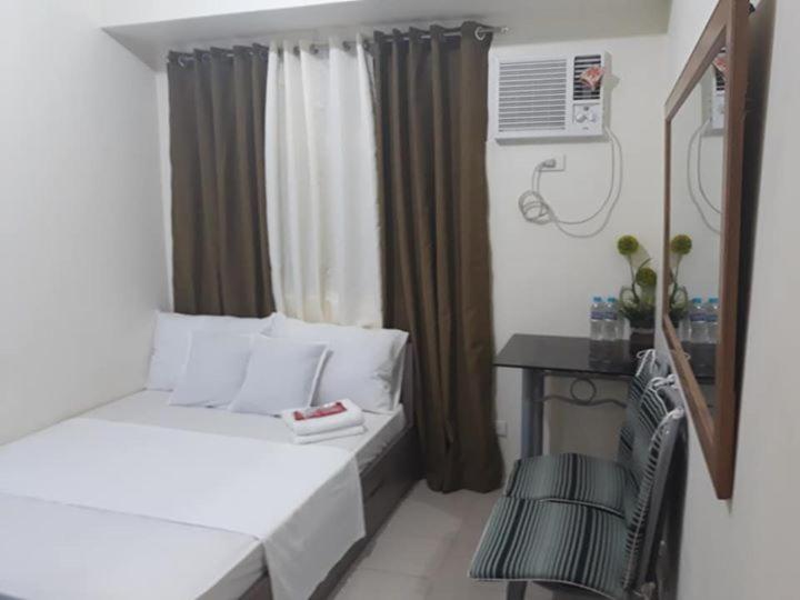 Cette petite chambre comprend un lit, un bureau et une fenêtre. dans l'établissement Edsa Urban Deca Tower Condo Unit with Wifi and Netflix, à Manille