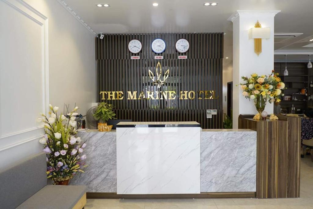 a lobby with a counter with clocks on the wall at Khách sạn Hải Quân - The Marine Hotel in Ha Long