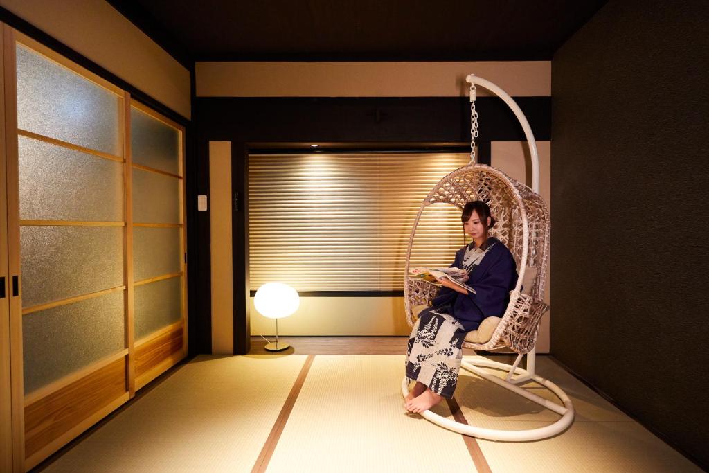 un homme assis sur une balançoire dans une pièce dans l'établissement Rinn Tenjincho, à Kyoto