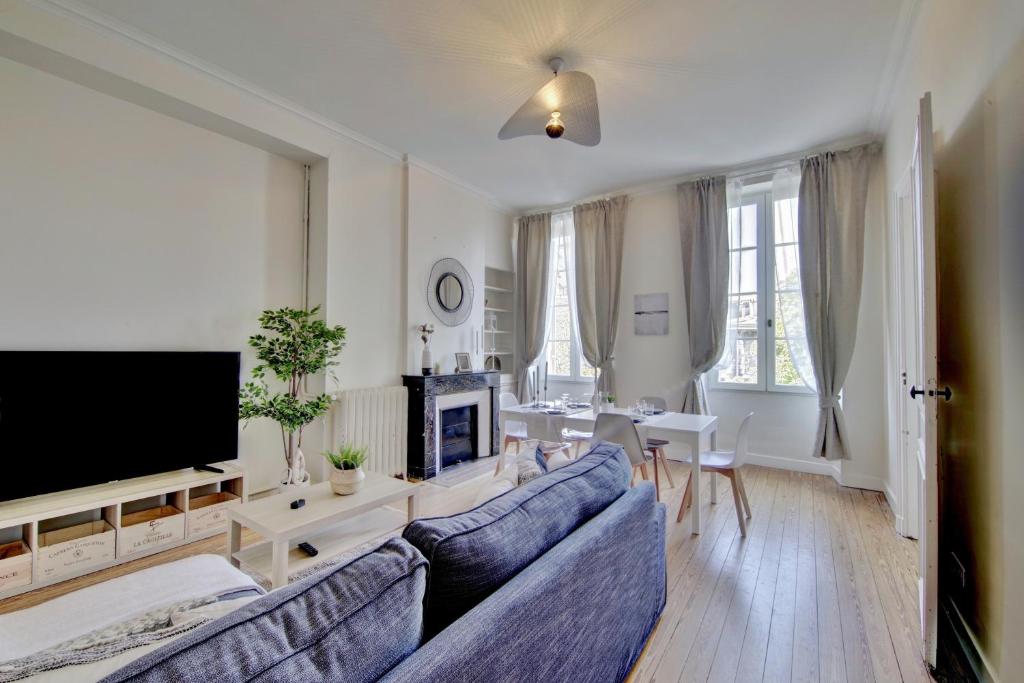 uma sala de estar com um sofá azul e uma televisão em Le Joyau by Cocoonr em Bordéus