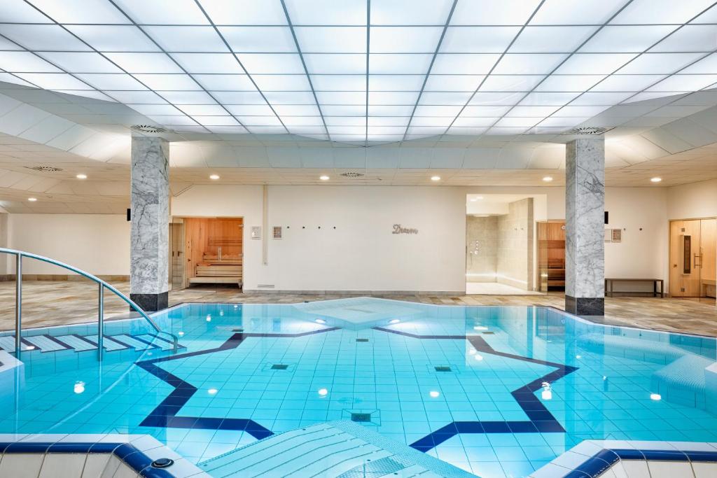 ein großer blauer Pool in einem Zimmer mit einer Decke in der Unterkunft H+ Hotel Wiesbaden Niedernhausen in Niedernhausen