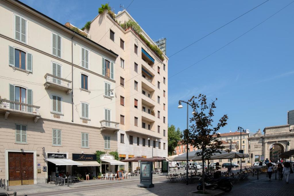 een stadsstraat met gebouwen, tafels en parasols bij Brera Apartments in Moscova in Milaan