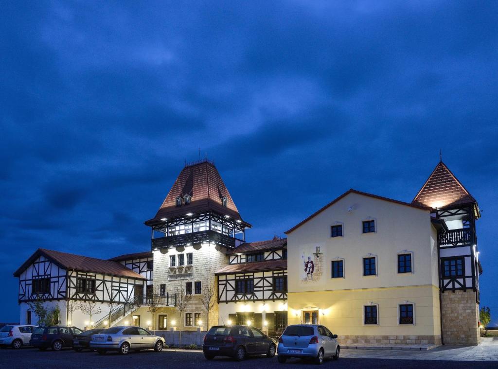 un gran edificio con coches estacionados frente a él en Hotel Castel Royal, en Timisoara