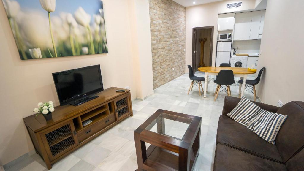 un soggiorno con TV e tavolo di RentalSevilla Apartamento en Barrio Santa Cruz con Parking a Siviglia