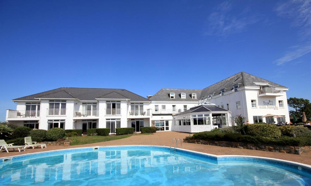 a large house with a large swimming pool in front of it at Hotel Jerbourg in St. Peter Port