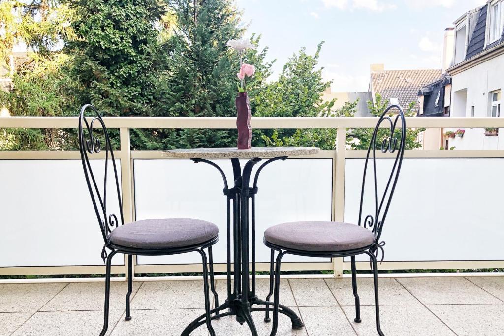 Duas cadeiras e uma mesa com um vaso na varanda em Wunderschöne Altbauwohnung mit Flair in Wuppertal em Wuppertal