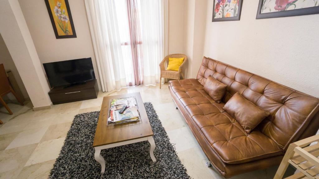 een woonkamer met een bruine leren bank en een salontafel bij RentalSevilla Gran apartamento en Barrio Santa Cruz Parking Gratuito in Sevilla