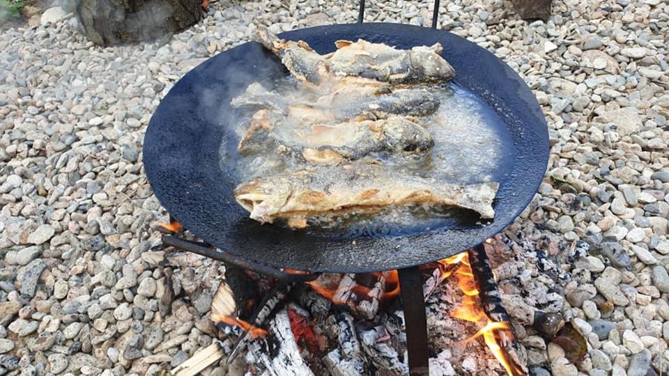 una parrilla con algo de comida encima del fuego en La Păstravaria Cerna en Rîu de Mori