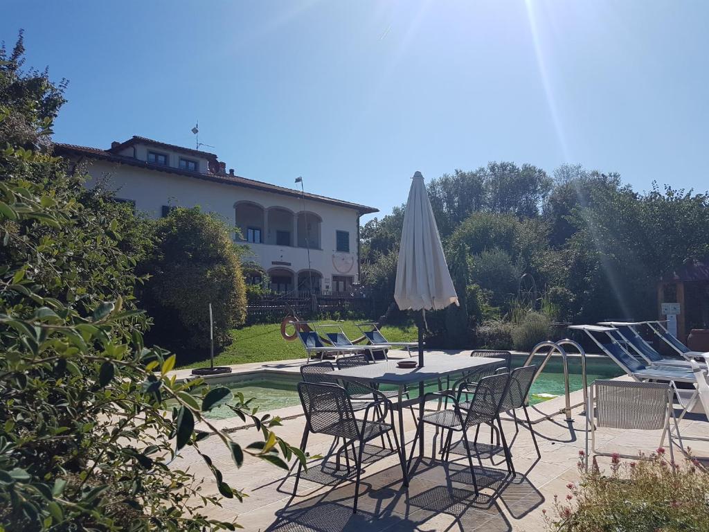 a patio with a table and chairs and a umbrella at Agriturismo Lucatello in Pratovecchio
