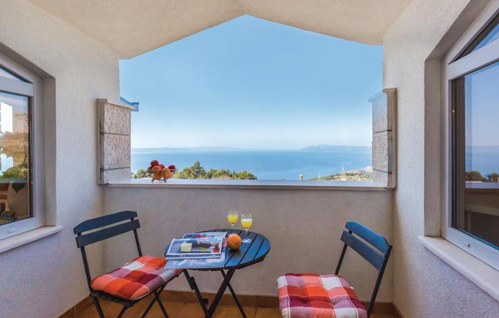 een tafel en stoelen op een balkon met uitzicht op de oceaan bij Vacation apartments Feniks in Tučepi