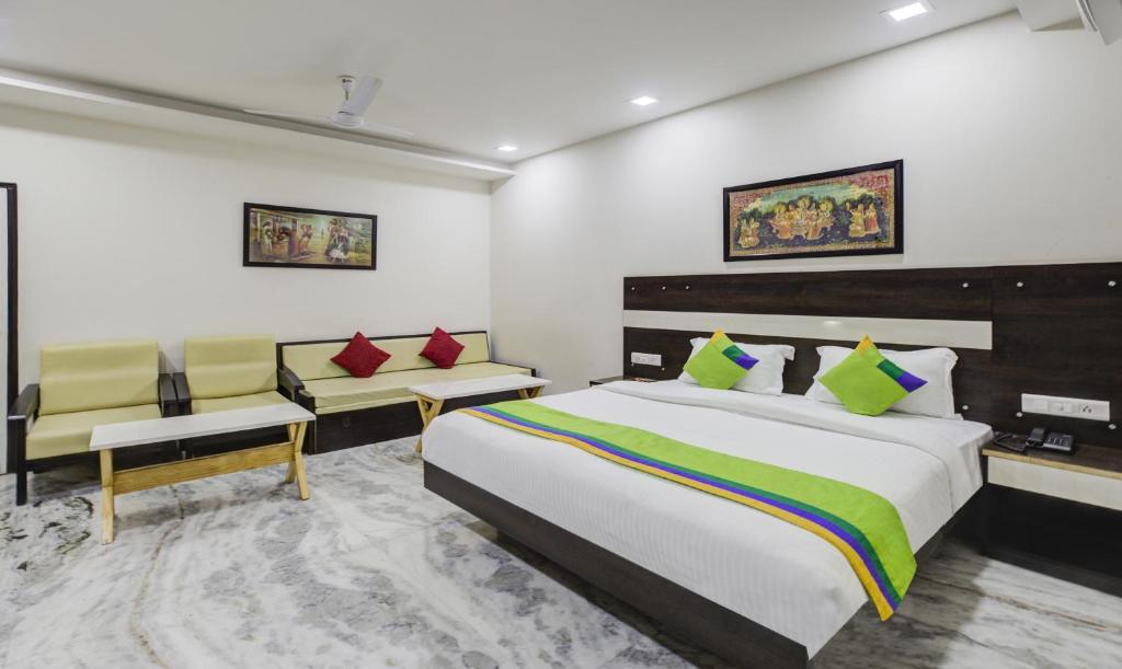 a bedroom with a large bed and two chairs at Hotel Royal Dezire Udaipur in Udaipur