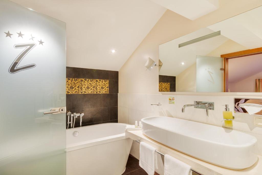 a white bathroom with a tub and a sink at Berg-Spa & Hotel Zamangspitze in Sankt Gallenkirch