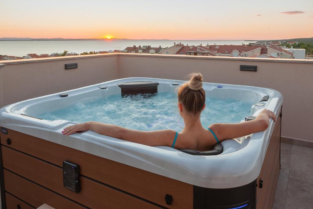 a woman sitting in a hot tub on a roof at Apartments Luana with private jacuzzi in Zadar