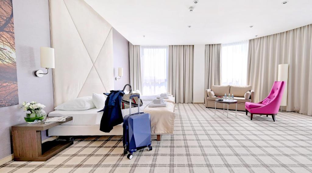 pokój hotelowy z łóżkiem i walizką w obiekcie Hotel Rzeszów w mieście Rzeszów