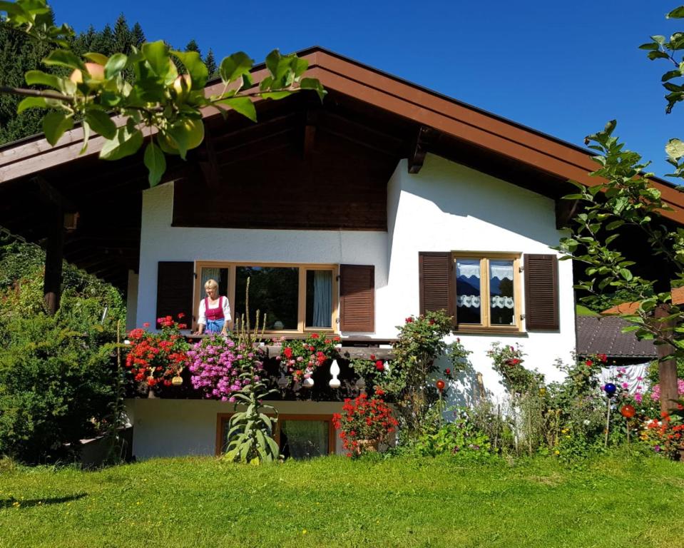 a woman standing on a balcony of a house with flowers at Ferienhaus Ursula in Klais