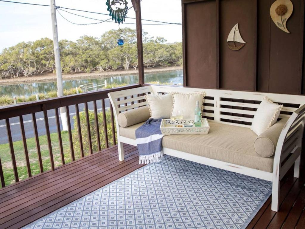 a porch with a couch and a view of the water at Kookas Nest - waterfront home, tranquil setting in Dunbogan