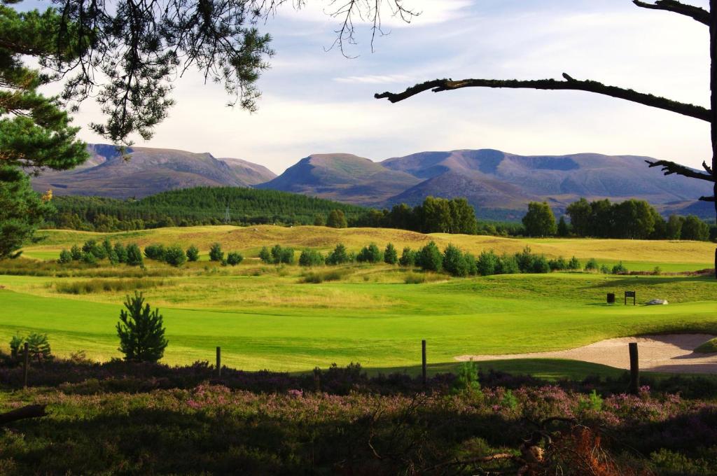 a view of a golf course with mountains in the background at Silverglades Holiday Homes in Aviemore