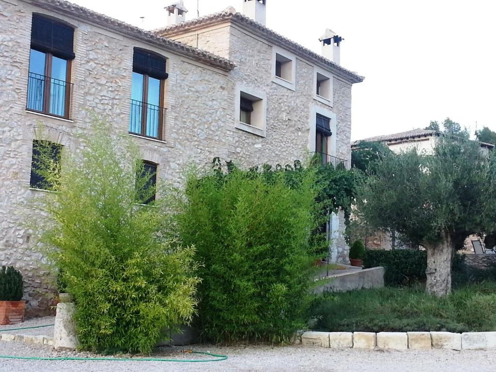 a stone building with bushes in front of it at Apartamentos rurales La Alquería del Pilar in Banyeres de Mariola