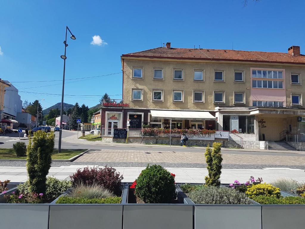 a building on a street with flowers in front of it at Hotel Ban&iacute;k Handlov&aacute; in Handlov&aacute;