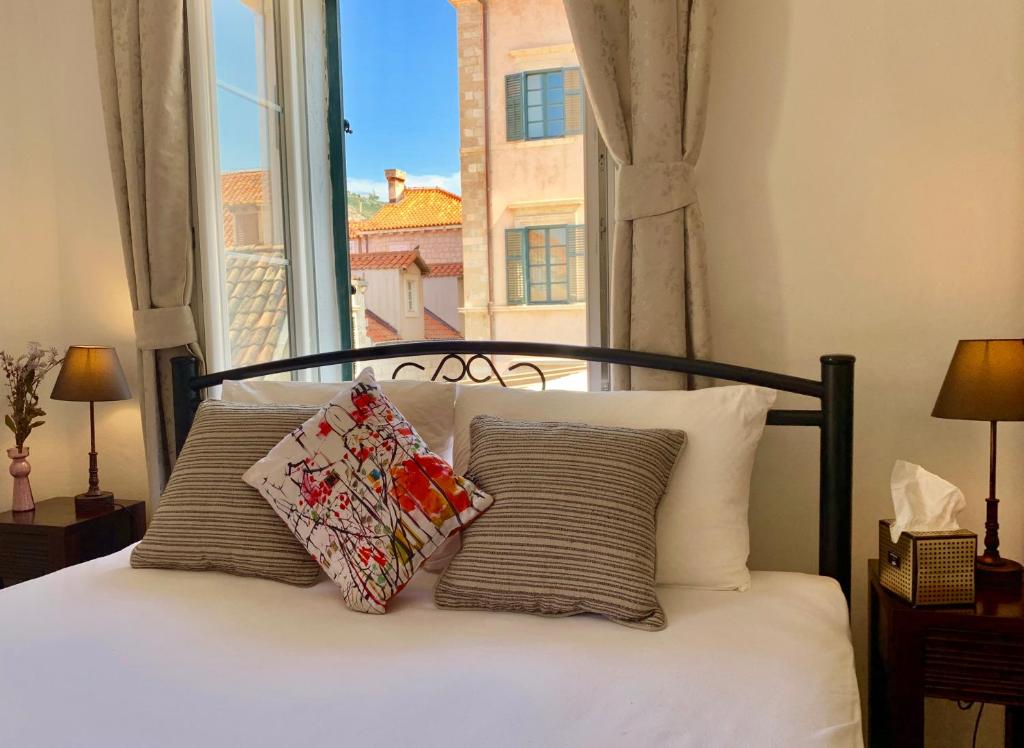 1 cama con 2 almohadas y ventana en Room 1783 Old town en Dubrovnik