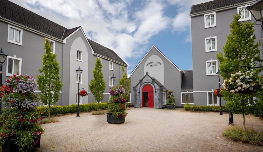 un bâtiment avec une porte rouge et des fleurs dans une cour dans l'établissement Temple Gate Hotel, à Ennis