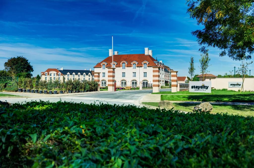 a large brick building with a clock on the side of it at Staycity Aparthotels Paris Marne La Vallée in Bailly-Romainvilliers