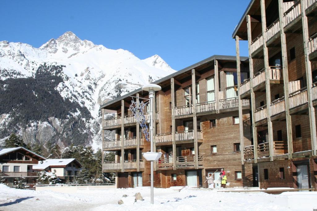 a hotel with a snow covered mountain in the background at Vacancéole - Résidence Les Chalets et Balcons De La Vanoise in La Norma