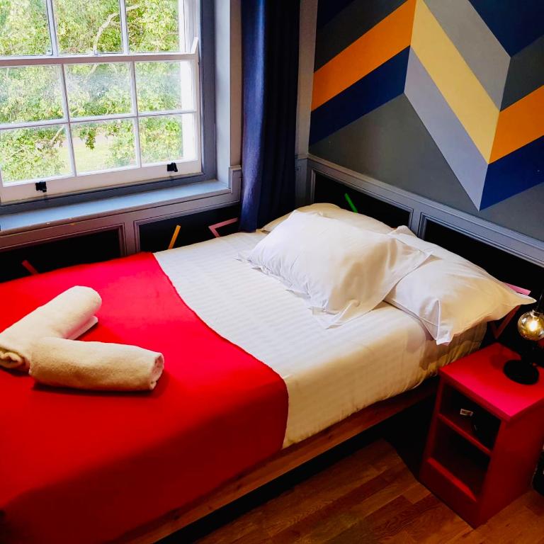 - une chambre avec un lit doté d'une couverture rouge et d'une fenêtre dans l'établissement KX Rooms Kings Cross, à Londres