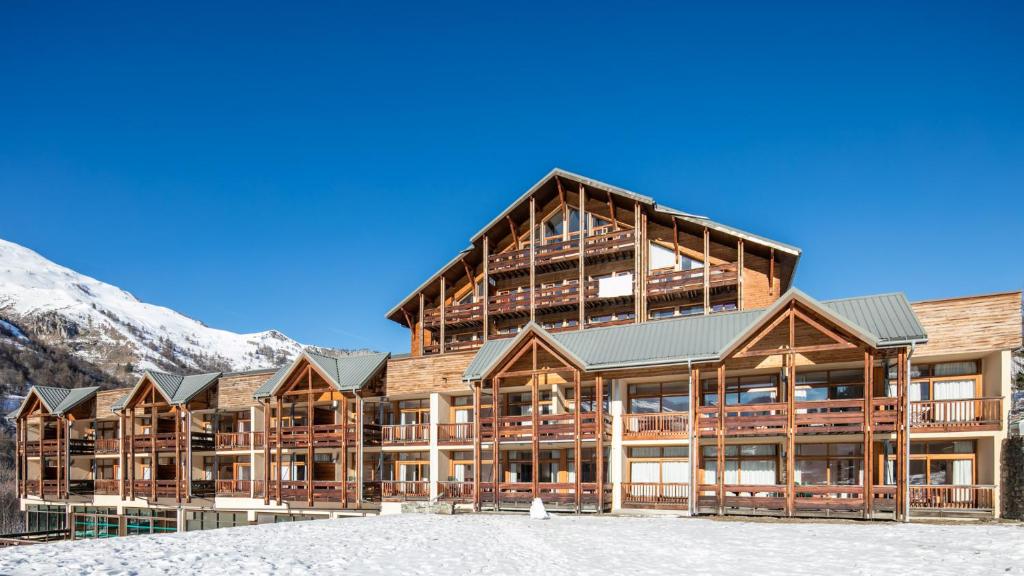 un grand lodge avec une montagne en arrière-plan dans l'établissement Vacancéole - Le Hameau de Valloire, à Valloire