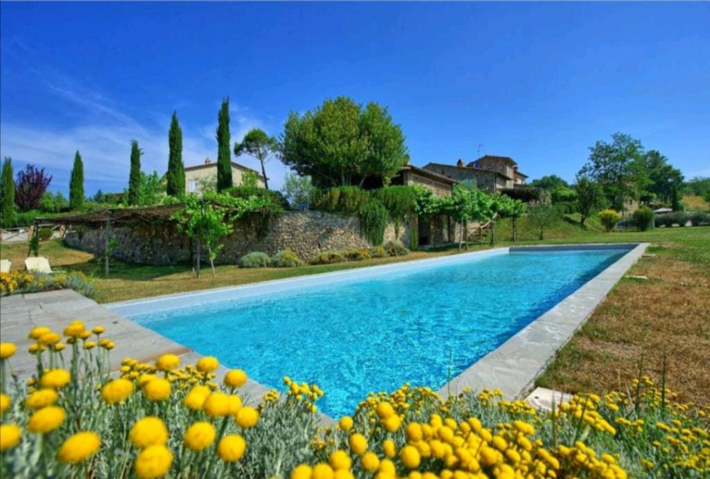 a swimming pool in front of a house with a garden at Tinaia in Anghiari