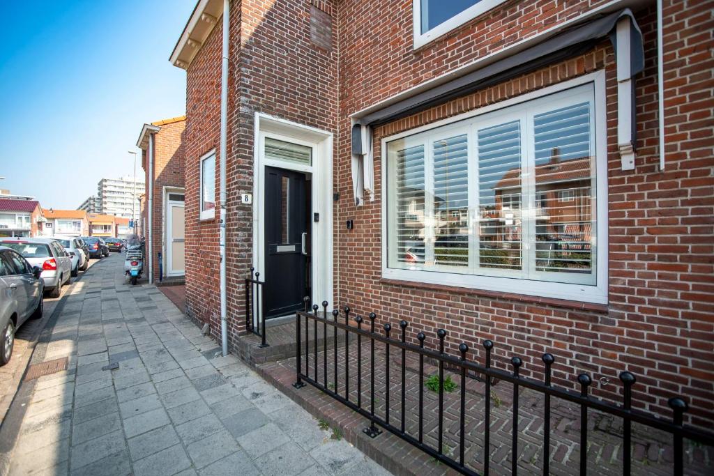 a brick building with a black fence next to a street at Bamboa Beachhouse in Zandvoort