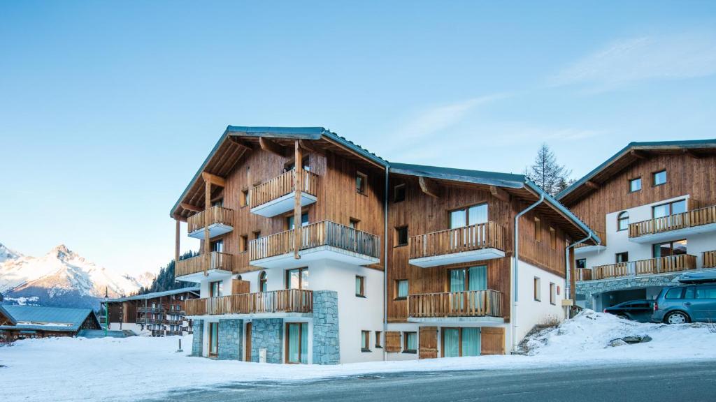 a large apartment building with snow on the ground at Vacancéole - Résidence Les Chalets de la Ramoure in Valfréjus