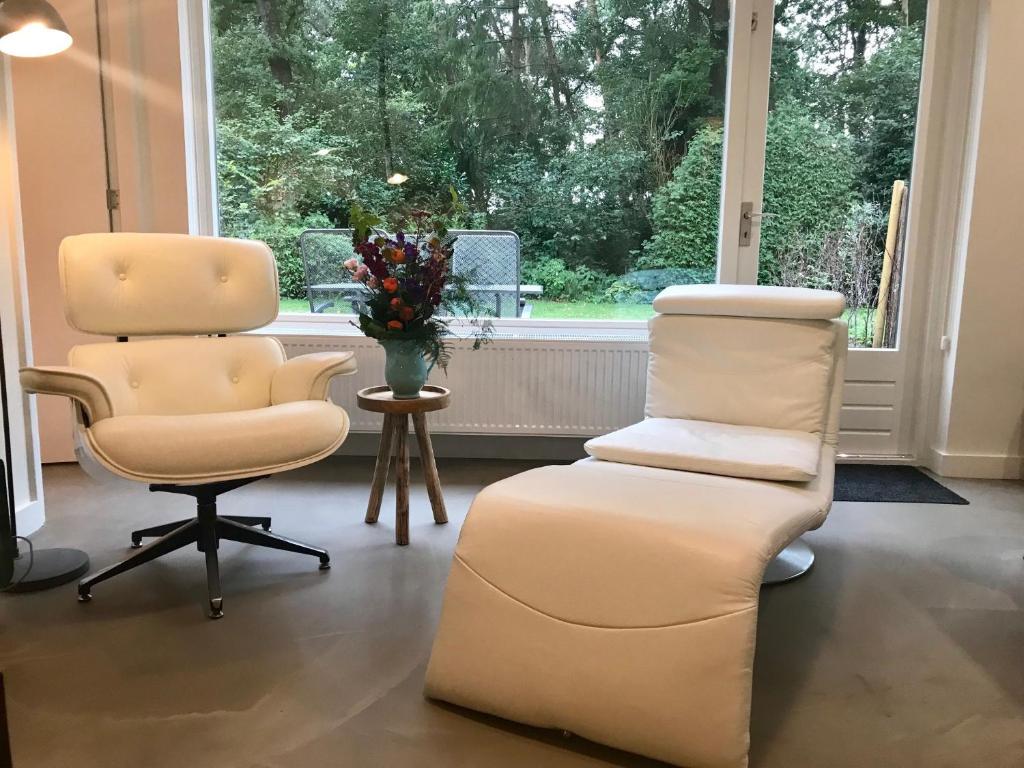 um salão com duas cadeiras e uma cadeira e um chairfolio em Natuurpark Hoefbos Boshuisje Veluwe em Otterlo
