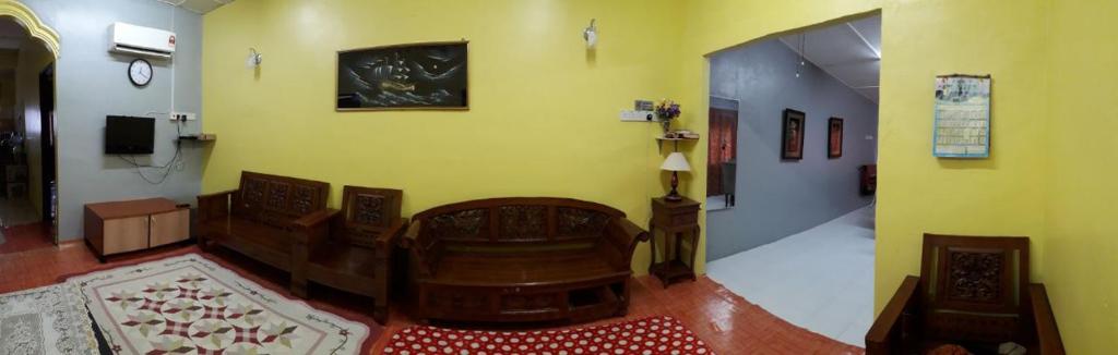 a living room with yellow walls and a couch and a television at Jitra homestay in Jitra